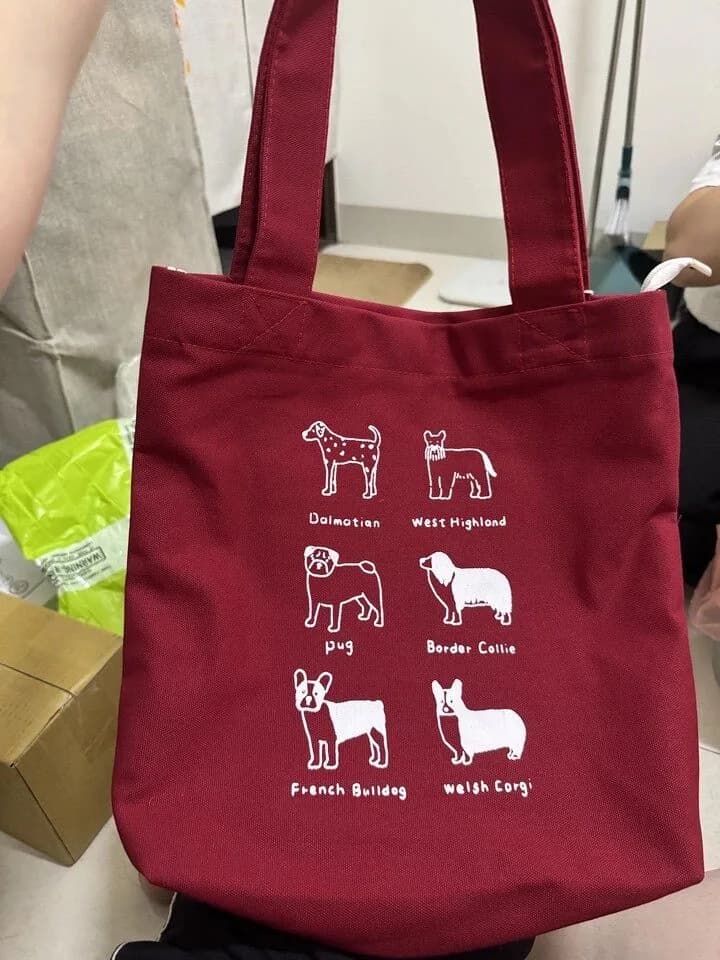 Red tote bag with white dog illustrations and lettering