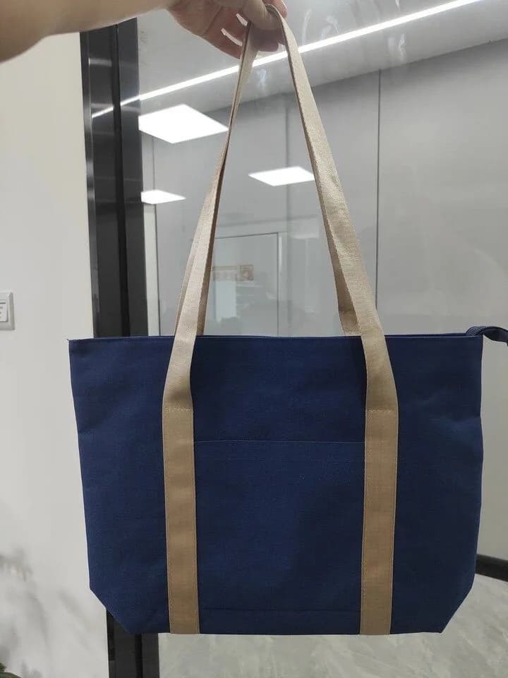 Navy tote bag with long natural-colour handles and a front pocket