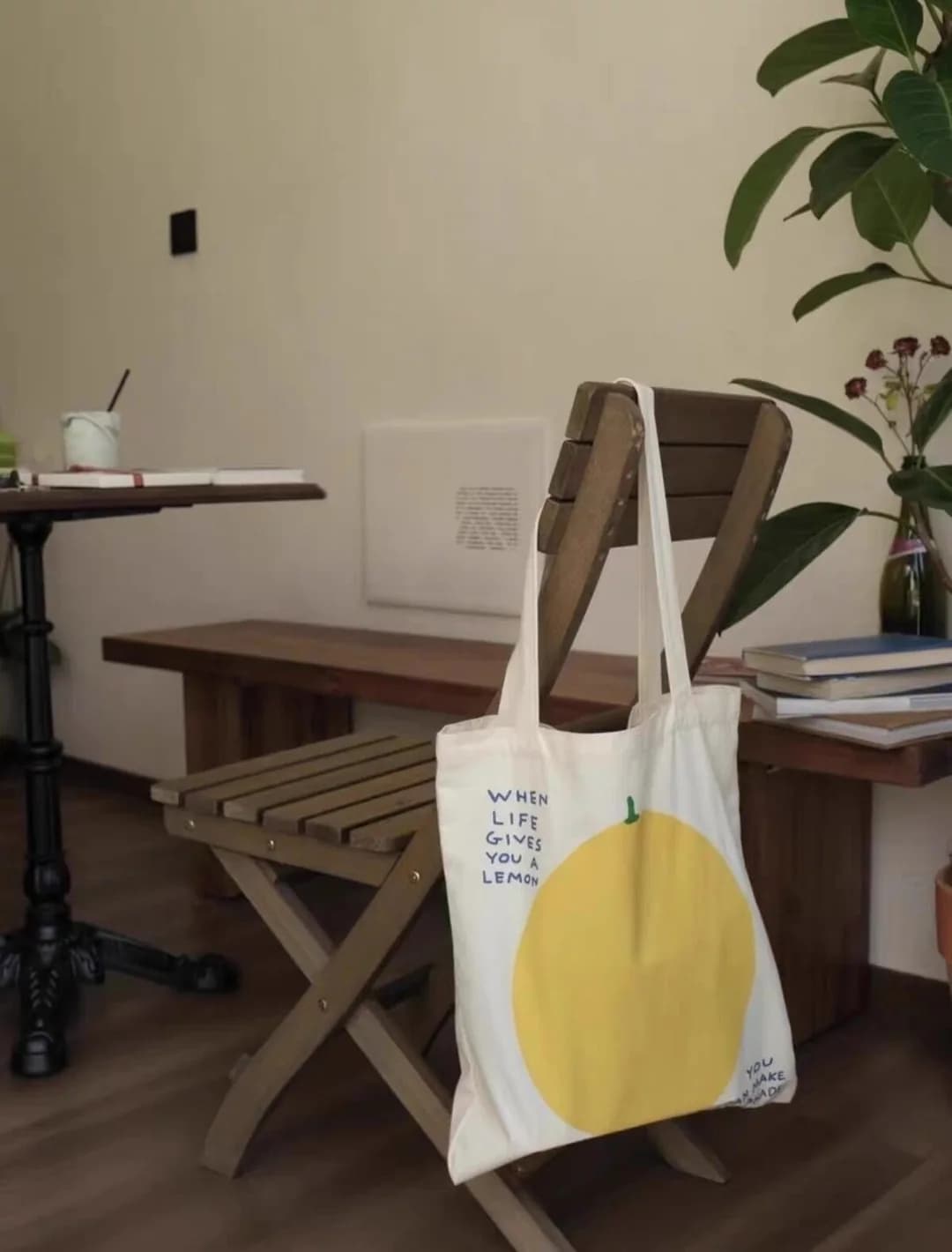 Natural-colour tote bag with a yellow lemon illustration hanging on a wooden chair