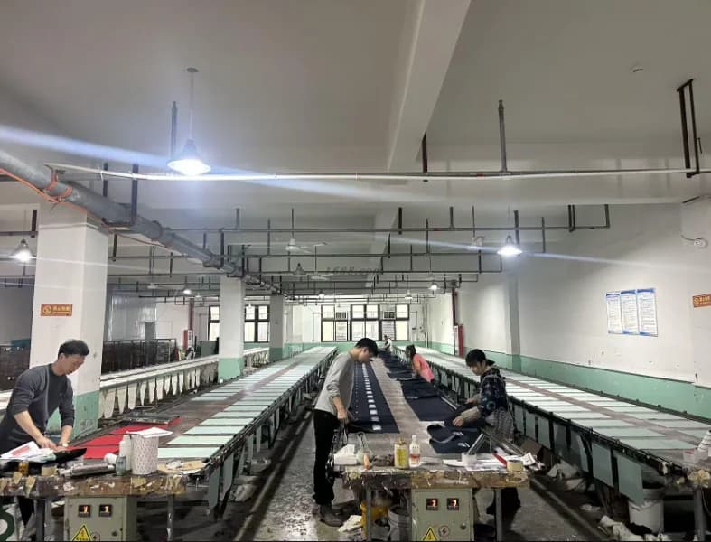 Operators working with screens along printing tables at a manufacturing partner facility