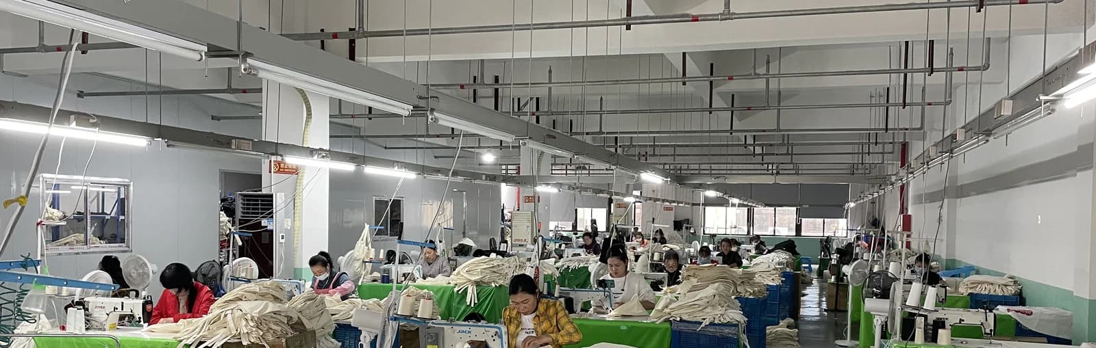 Rows of sewing workstations and operators in a manufacturing partner workshop